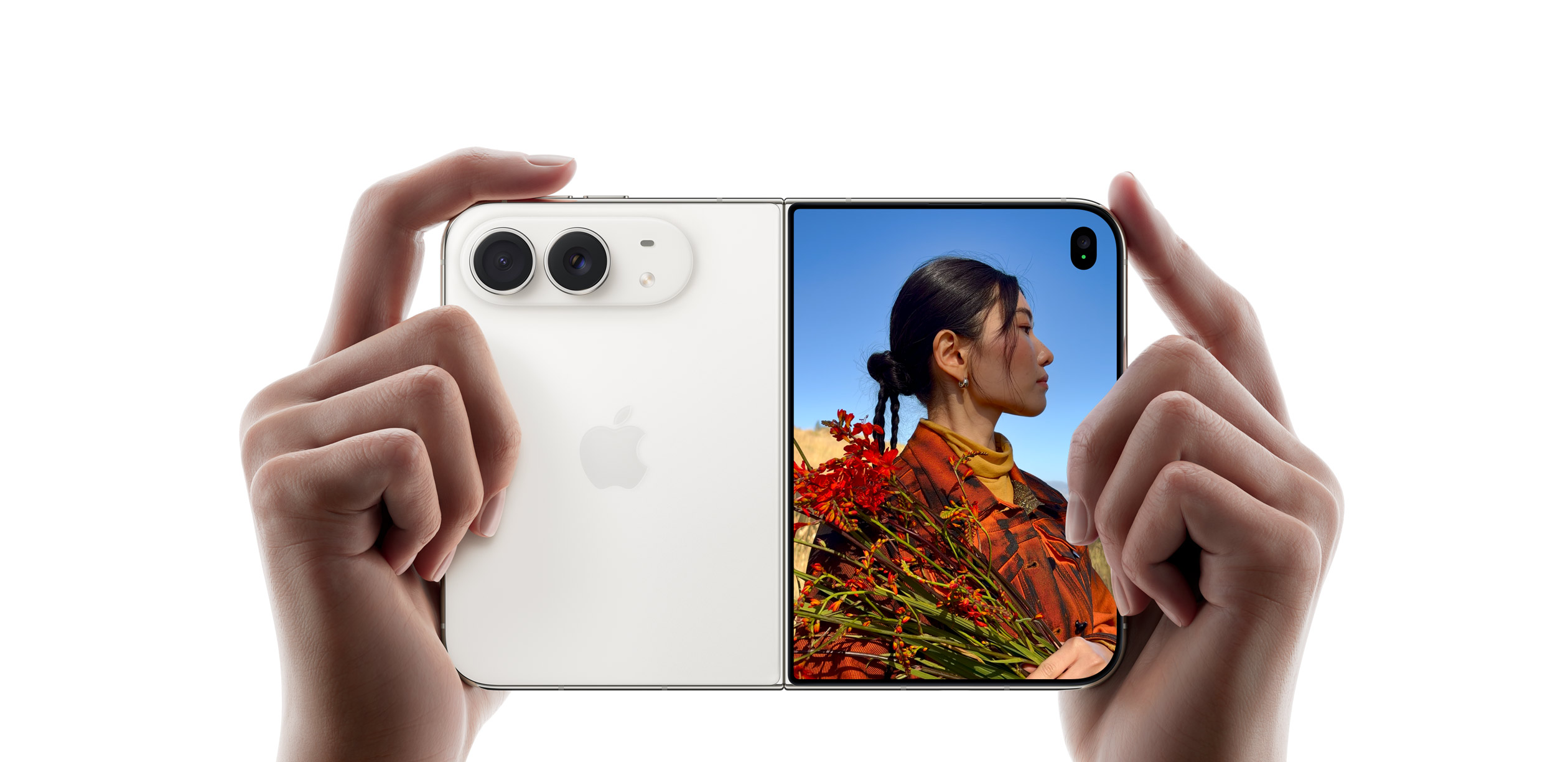 Белый iPhone Duo раскрыт в руках, снимает фотографию с помощью основной камеры