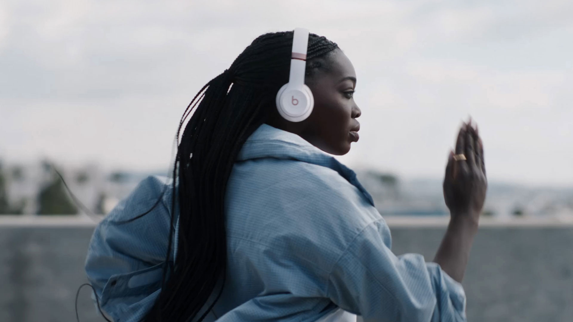 Девушка в синей куртке в Beats Solo 4 на набережной, наушники видны крупным планом