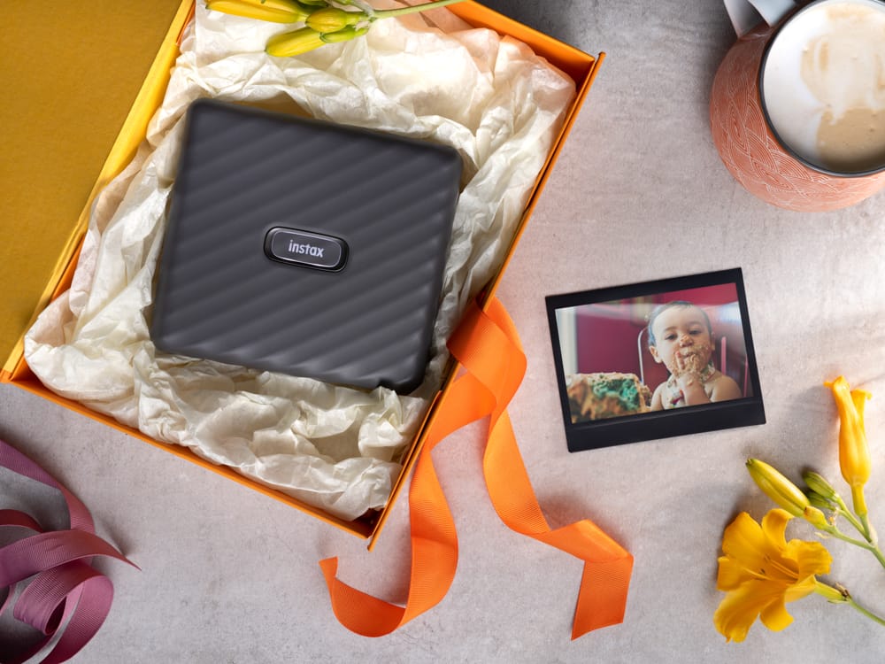 Fujifilm Instax Link Wide White в подарочной упаковке рядом с напечатанным снимком ребёнка
